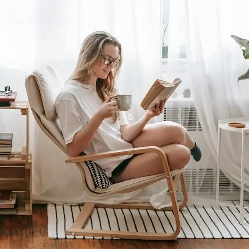 Luister naar je lichaam, vind rust en krijg meer energie Vrouw luistert naar haar lichaam, leest een boek, geniet van thee en krijgt meer energie door rust.