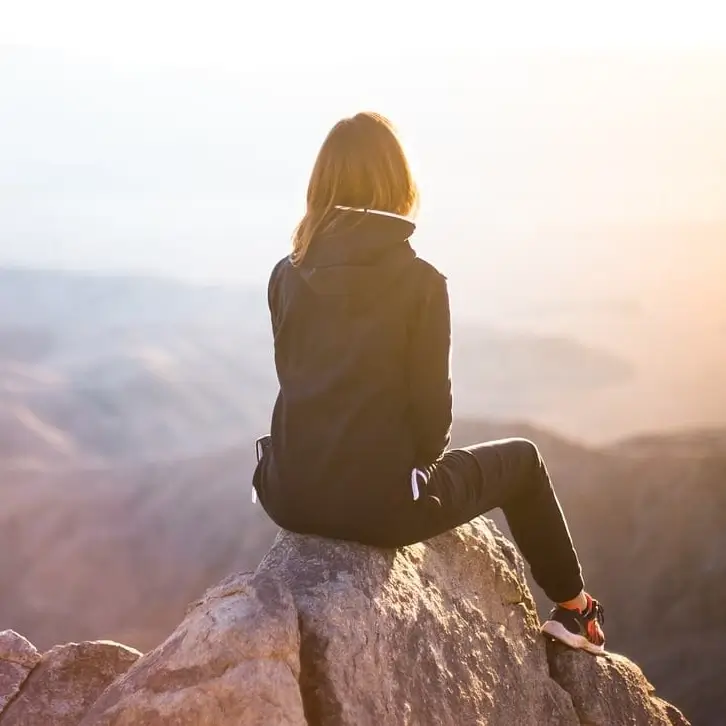 _vrouw-herstelt-van-weinig-energie-met-oefening Vrouw op bergtop voelt zich energiek na eenvoudige oefening om meer energie te krijgen